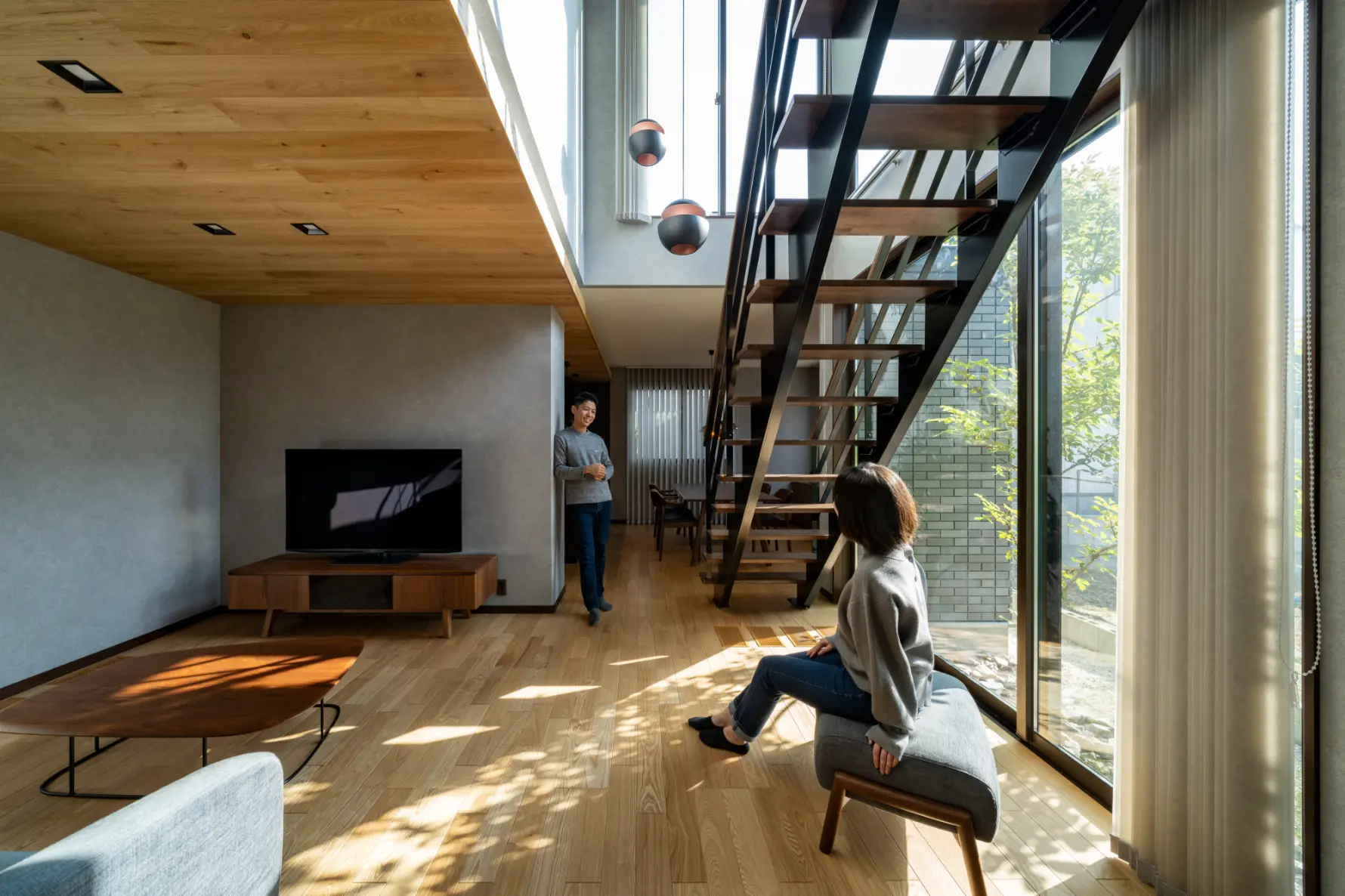 木漏れ日の入る吹き抜けリビングで歓談するご夫妻