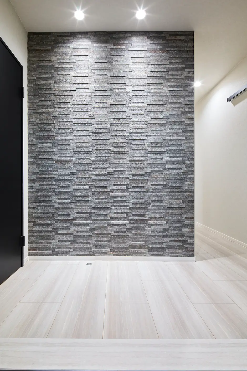 グレーの石目調アクセントウォールが特徴的な玄関スペース