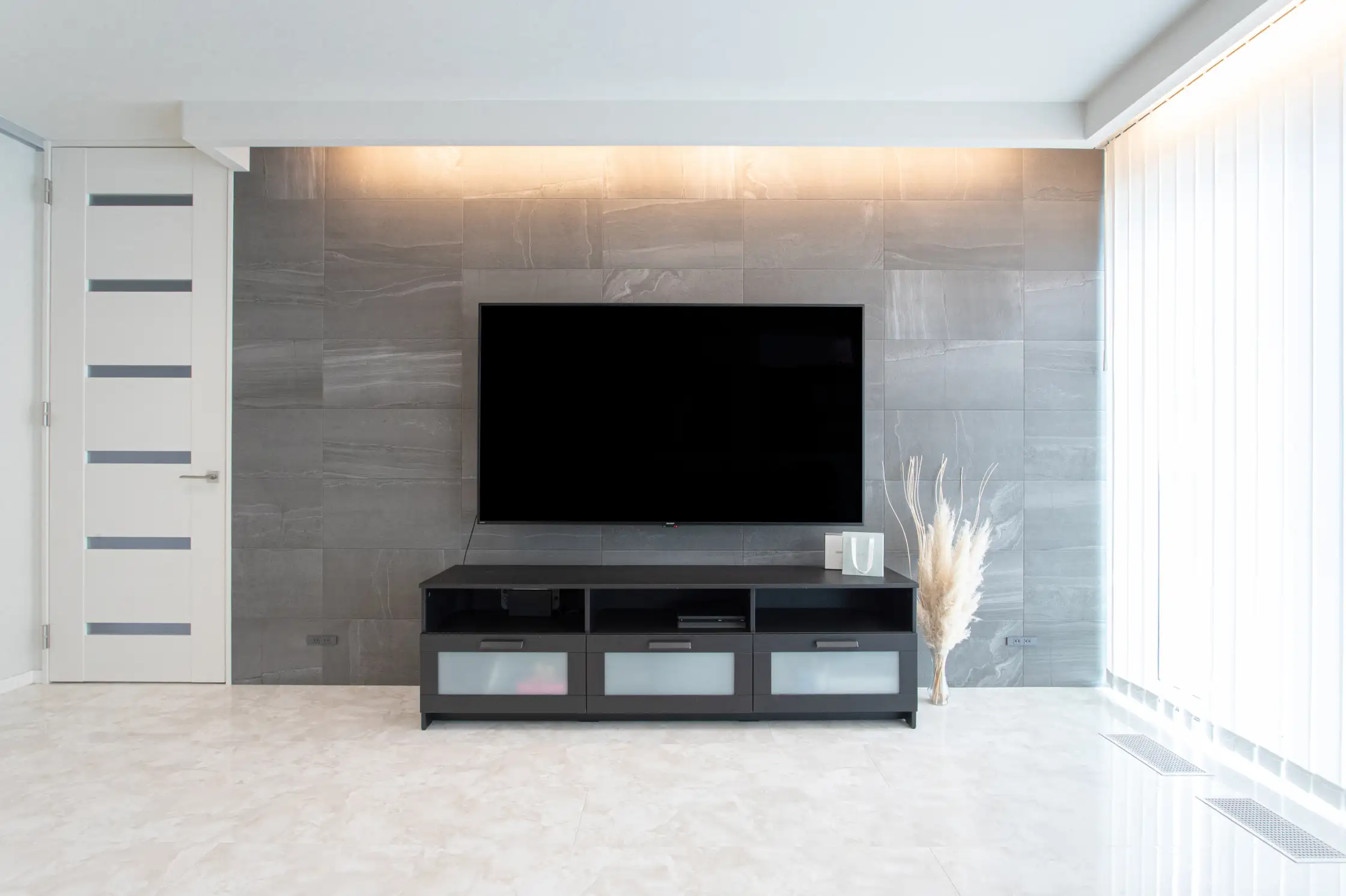 壁かけのテレビとL字型の間接照明が見えるリビング