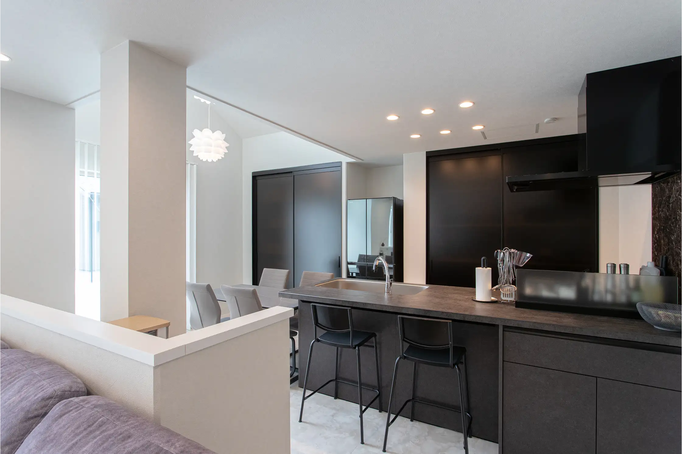 ダークトーンの対面型キッチンとカウンターとダイニングテーブル