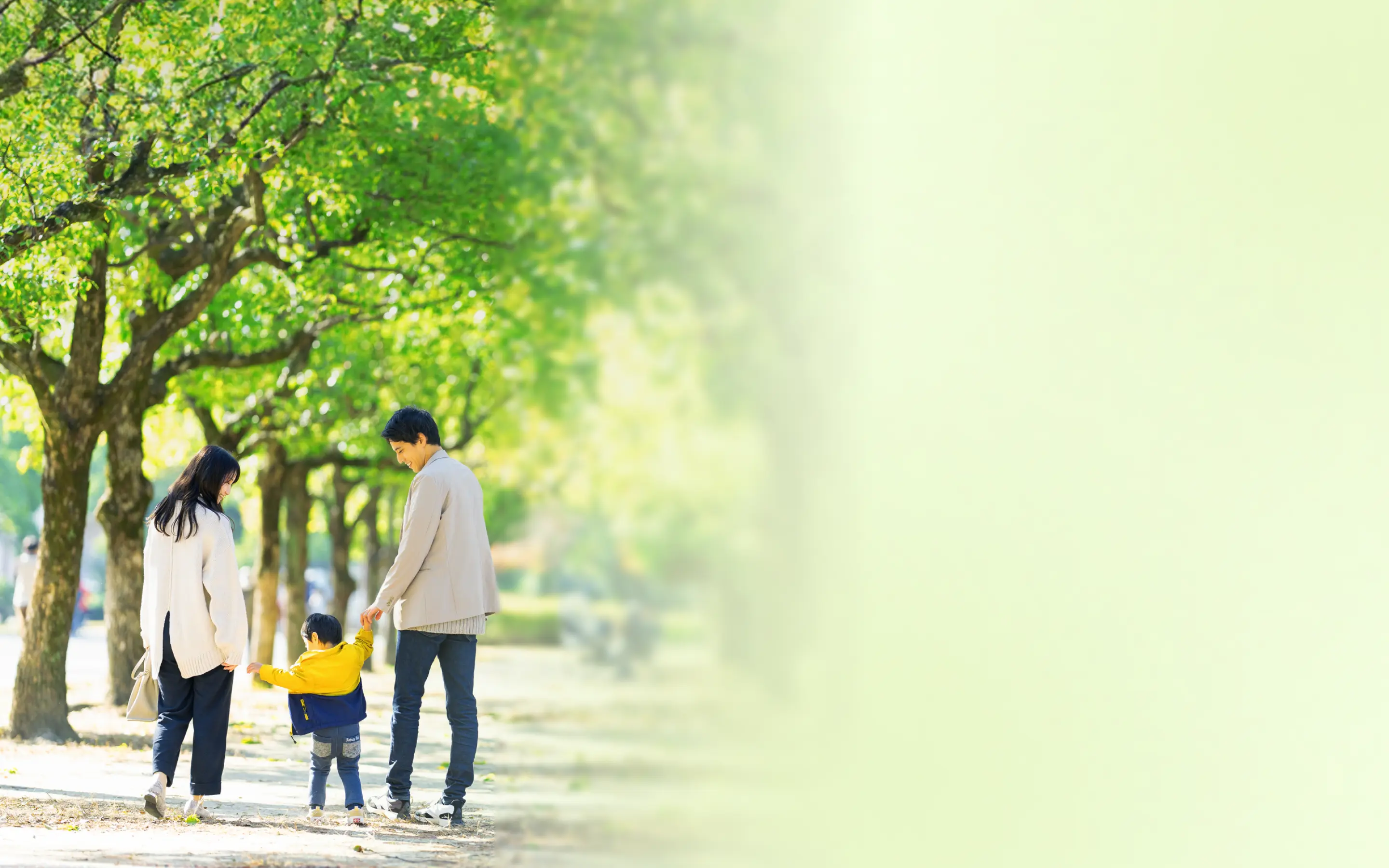 緑道を歩く夫婦と子