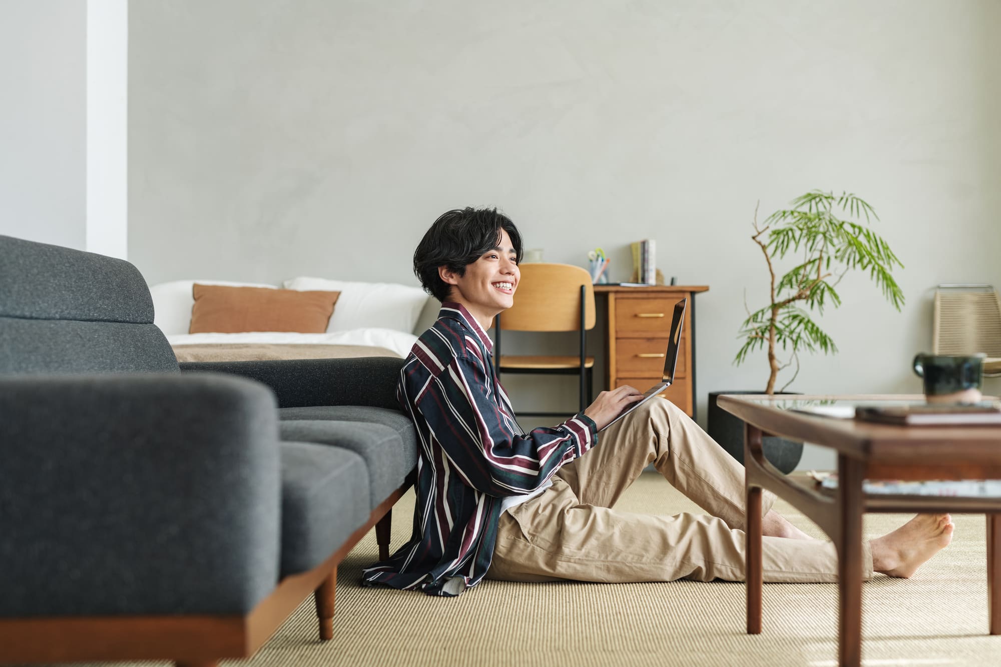 ナチュラルなインテリアに囲まれたリビングでソファにもたれてリラックスしている様子