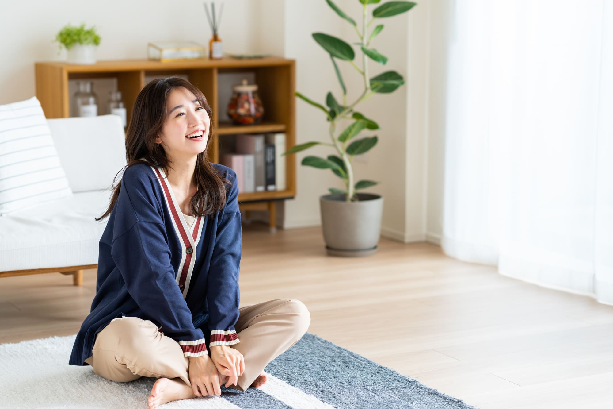 自然光が差し込むリビングで床に座ってくつろぐ人の様子