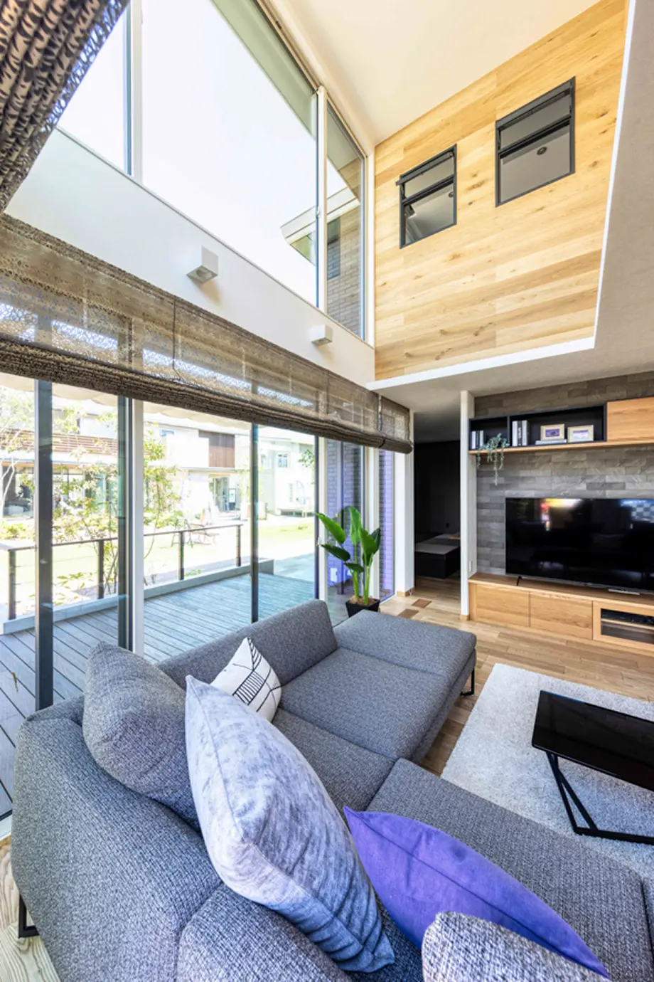 壁の一面に大型ガラスを採用した吹き抜けのあるリビング