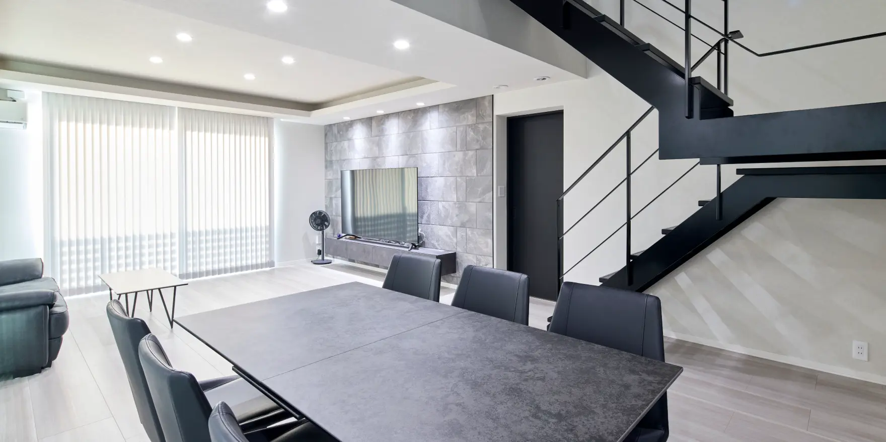 黒のスケルトン階段が映えるモノトーン調の明るいLDK