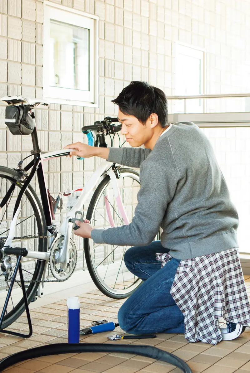 バルコニーで自転車のメンテナンスをする男性
