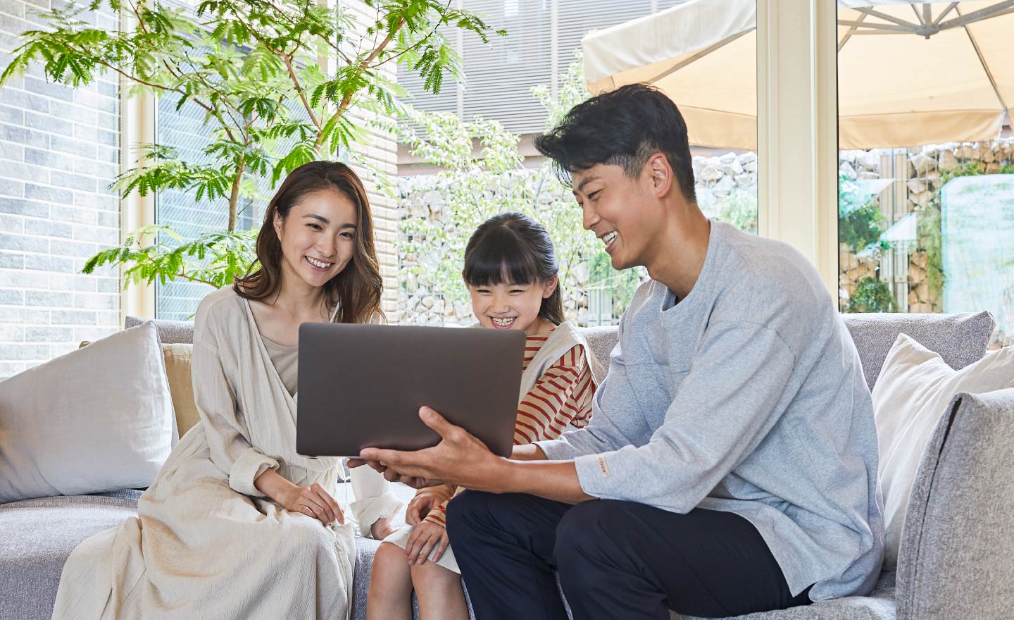 リビングでパソコン画面を閲覧する、母親、娘、父親